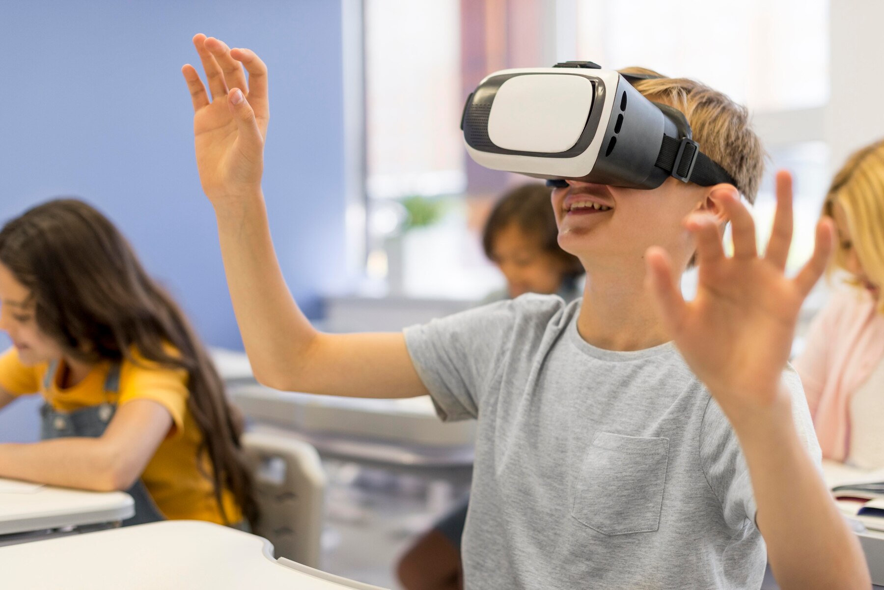 A student wearing a VR headset raises their hand excitedly in a classroom filled with peers engaged in learning activities.